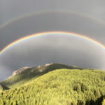 A double rainbow over a mountain covered in forest